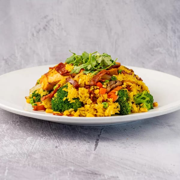 ChuMinh Tofu's vibrant Vietnamese fried rice with tofu, broccoli, carrots, and cilantro on a white plate.