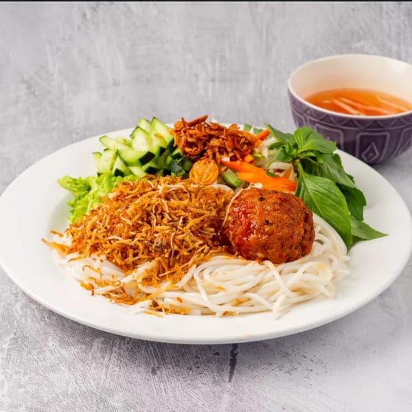 ChuMinh Tofu's Vietnamese dish with noodles, a meatball, fried onions, and fresh vegetables.