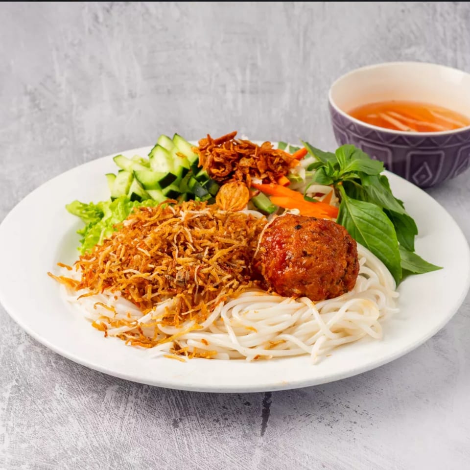 ChuMinh Tofu's Vietnamese dish with noodles, a meatball, fried onions, and fresh vegetables.