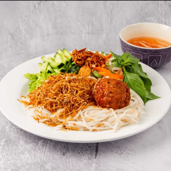 Vietnamese vermicelli noodles with a meatball, fried onions, fresh herbs, and a side of broth.