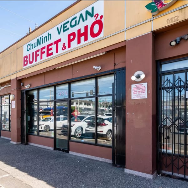 Exterior of ChuMinh Tofu, a Vietnamese vegan buffet and pho restaurant, with large windows reflecting cars.