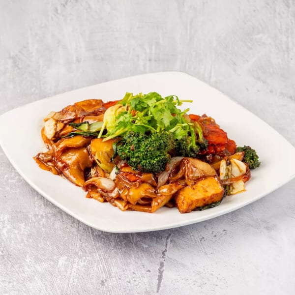 ChuMinh Tofu's Vietnamese stir-fried noodles with tofu, broccoli, and cilantro on a white plate.