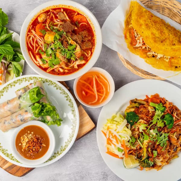 A vibrant spread of Vietnamese dishes, including pho, spring rolls, a savory crepe, and noodles.