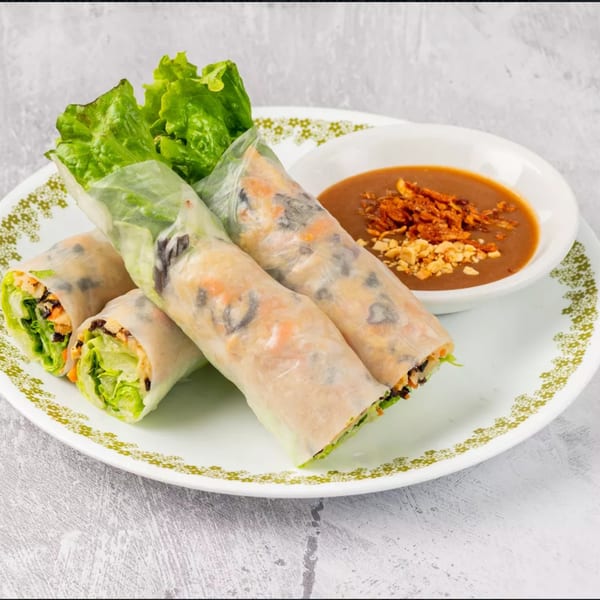 Three fresh Vietnamese spring rolls with lettuce, tofu, and carrots, served with a peanut dipping sauce.